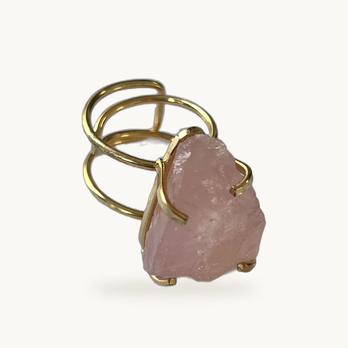 Bague Rosa Bruta ORA plaqué or, quartz rose brut serti griffes sur anneau spirale ajustable, fond beige