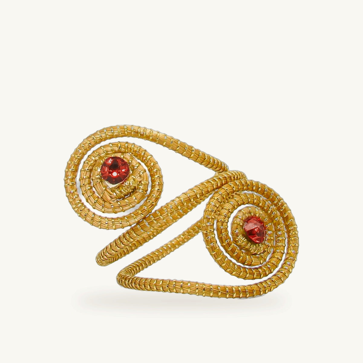 Bague Duetto ORA en capim dourado, double spirale cousue main et cristaux rouges, fond beige