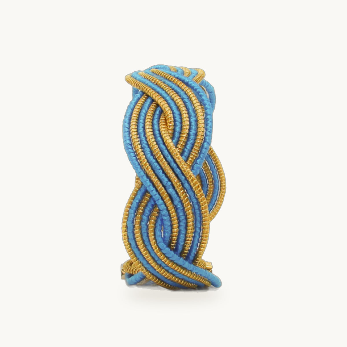 Manchette Caracol ORA alternée bleu ciel, capim dourado tressé main en nœud infini, fond beige