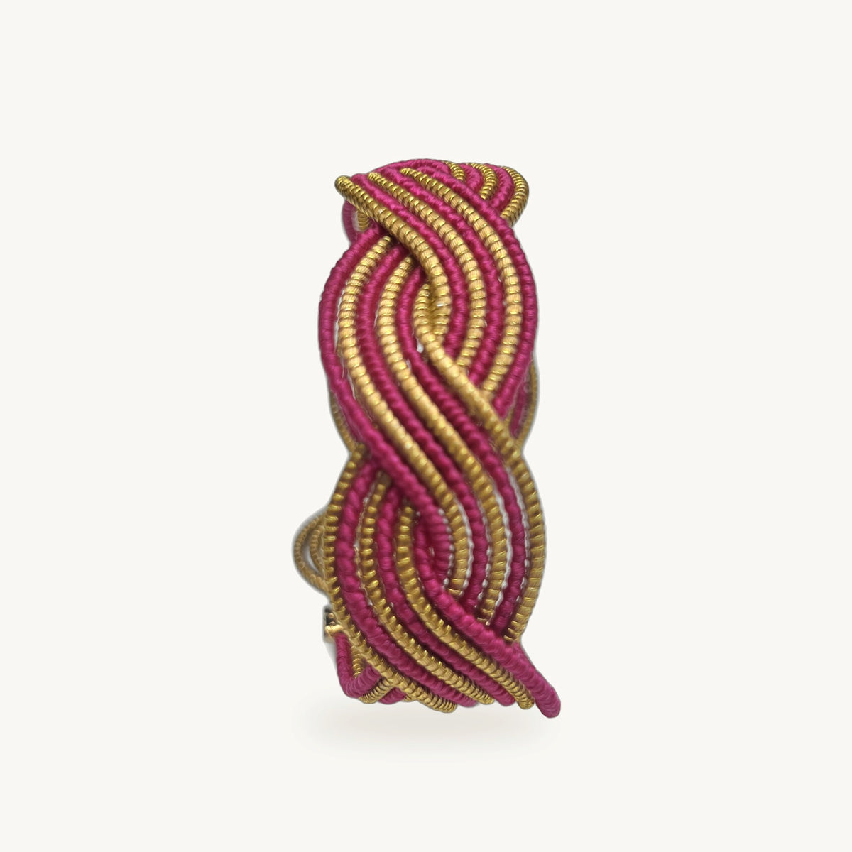 Manchette Caracol ORA alternée rose fuchsia, capim dourado tressé main en nœud infini, fond beige