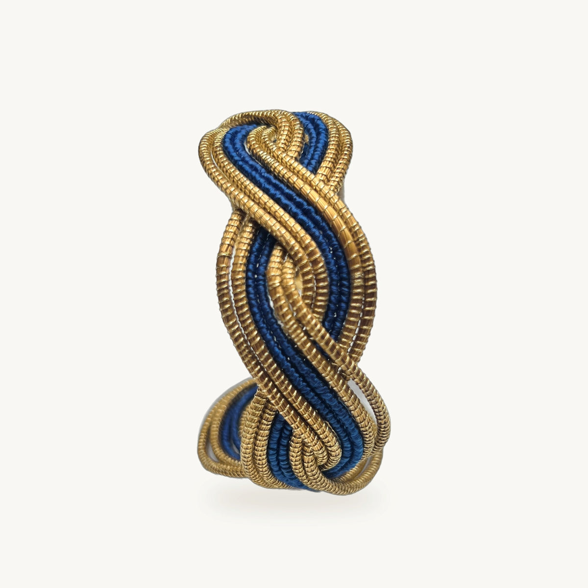 Manchette Caracol ORA bayadère bleu roi, capim dourado tressé main en nœud infini, fond beige