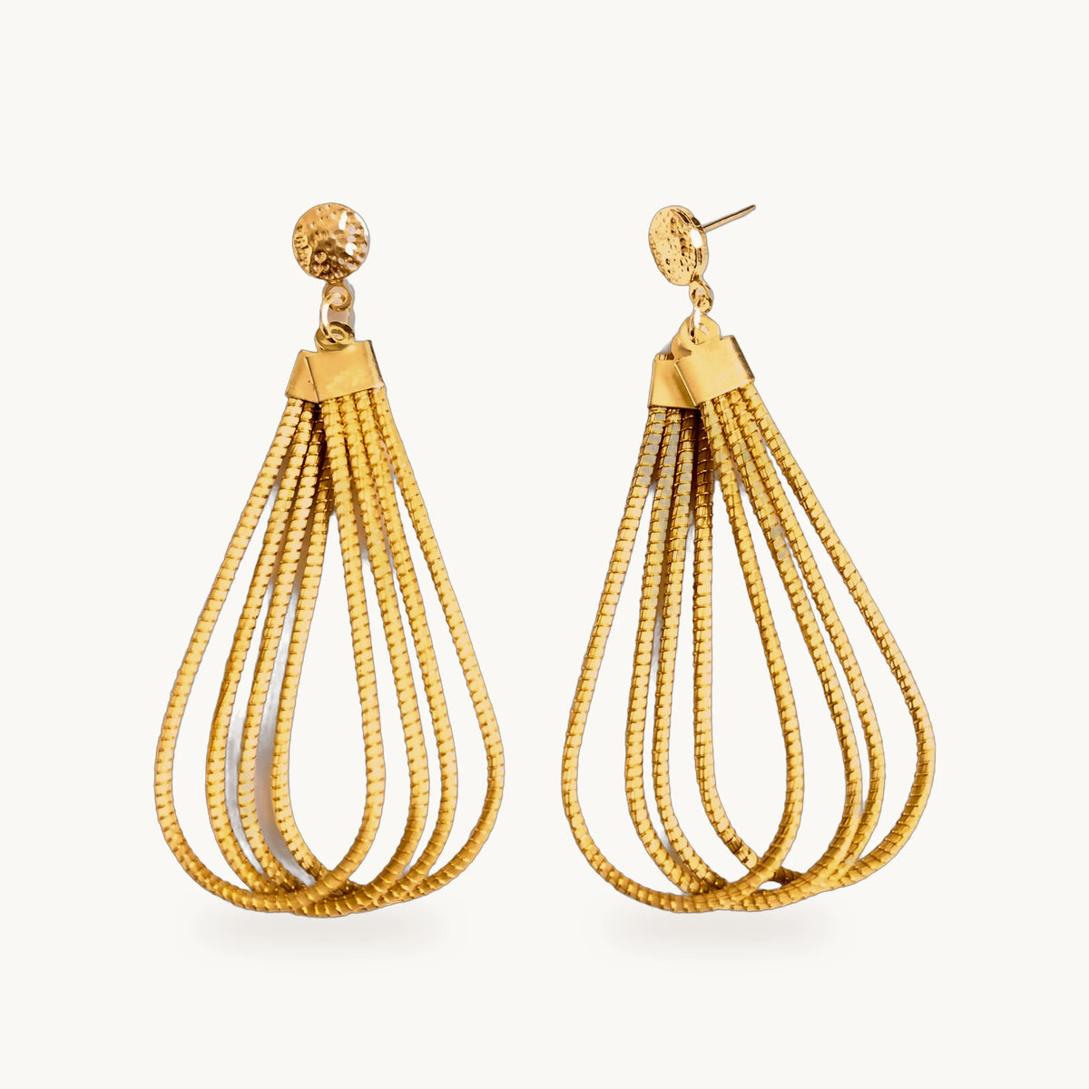 Boucles d'oreilles Gota ORA en forme de goutte, or végétal, sur fond beige