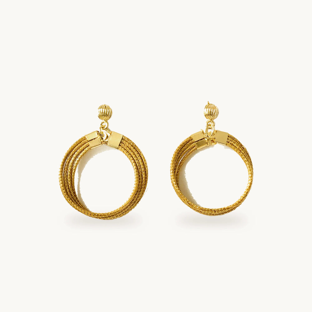 Boucles d'oreilles Lola ORA, quatre anneaux dorés en or végétal, sur fond beige