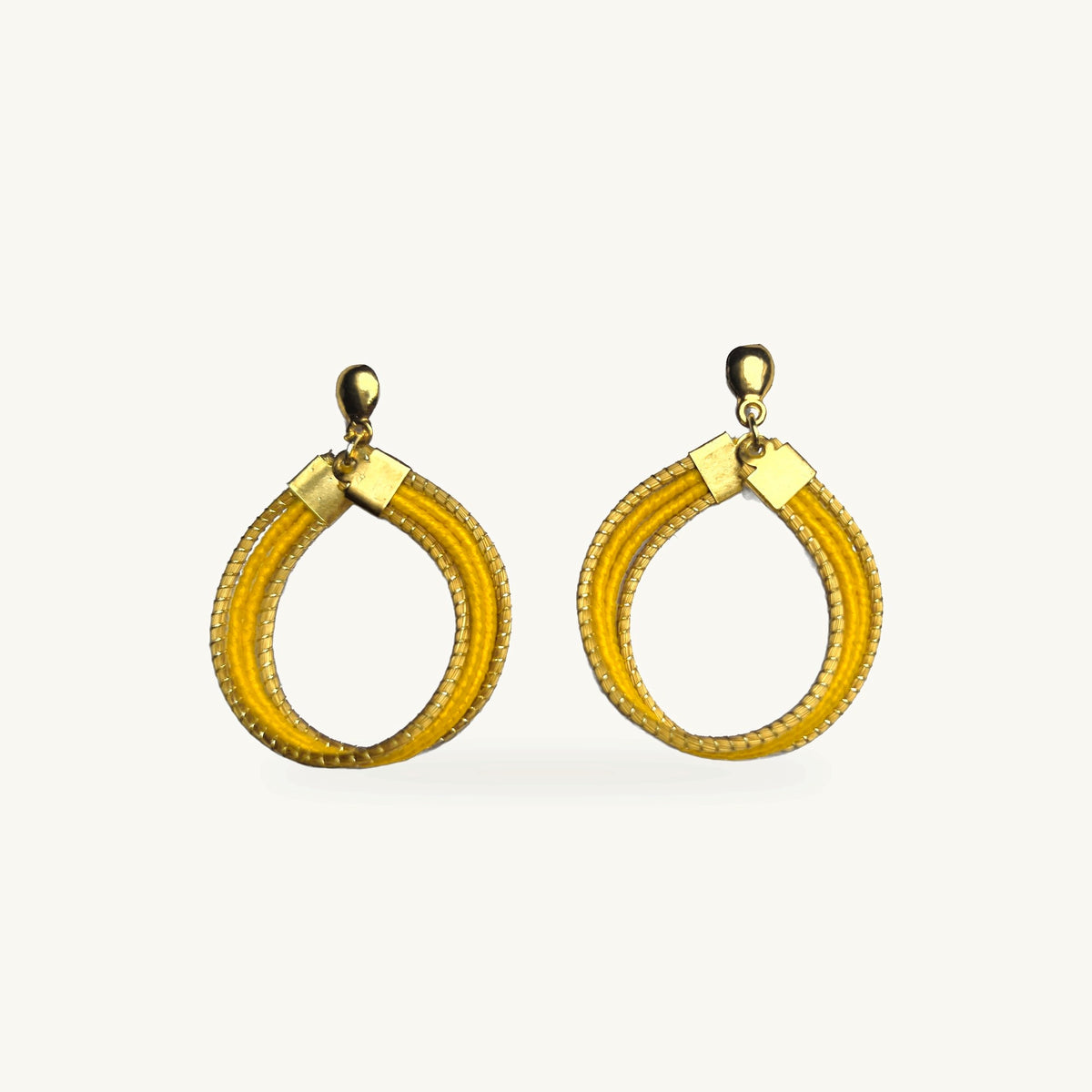 Boucles d'oreilles Lola Arco-Íris ORA jaunes, capim dourado tressé main, fond beige