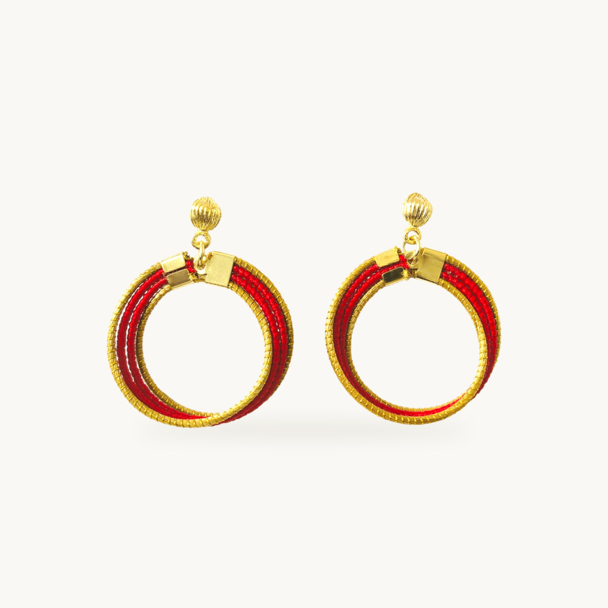 Boucles d'oreilles Lola Arco-Íris ORA rouges, anneaux de capim dourado tressés main, fond beige