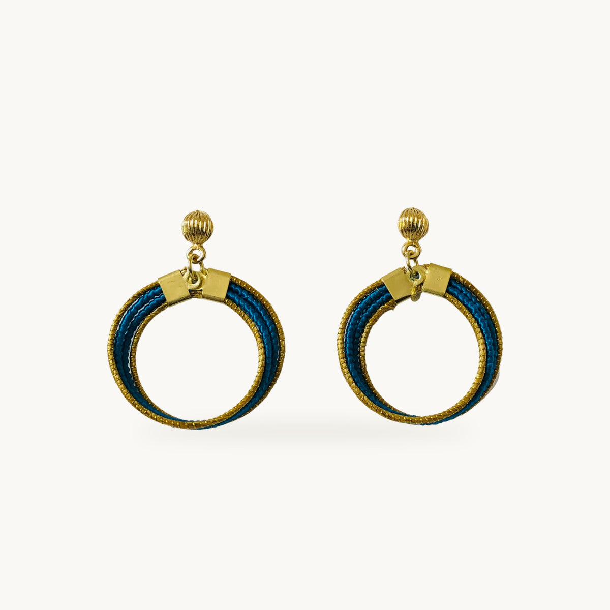 Boucles d'oreilles Lola Arco-Íris ORA bleu pétrole, capim dourado tressé main, fond beige